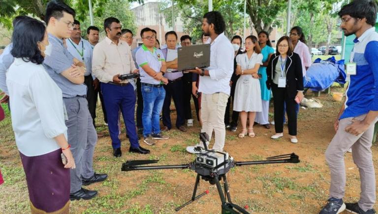 A staff member from the International Crops Research Institute for the Semi-Arid Tropics (ICRISAT) demonstrates the application of drones in advancing precision agriculture techniques. Photo credit: Landell Mills.